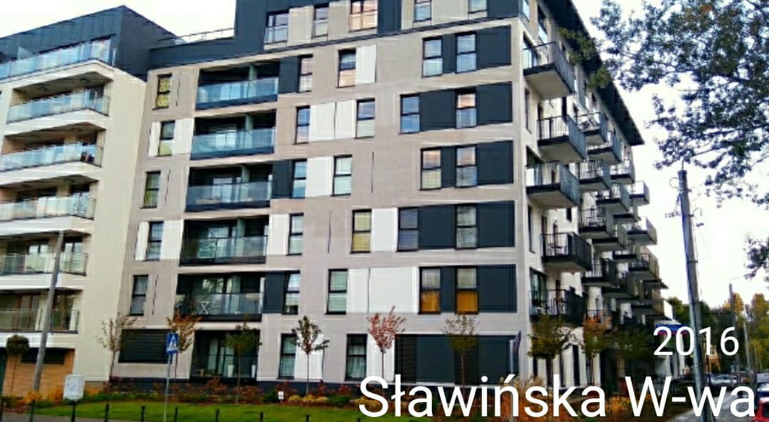 Nowoczesny budynek mieszkalny z balkonami i szklanymi balustradami, widok z poziomu ulicy, zieleń w tle.