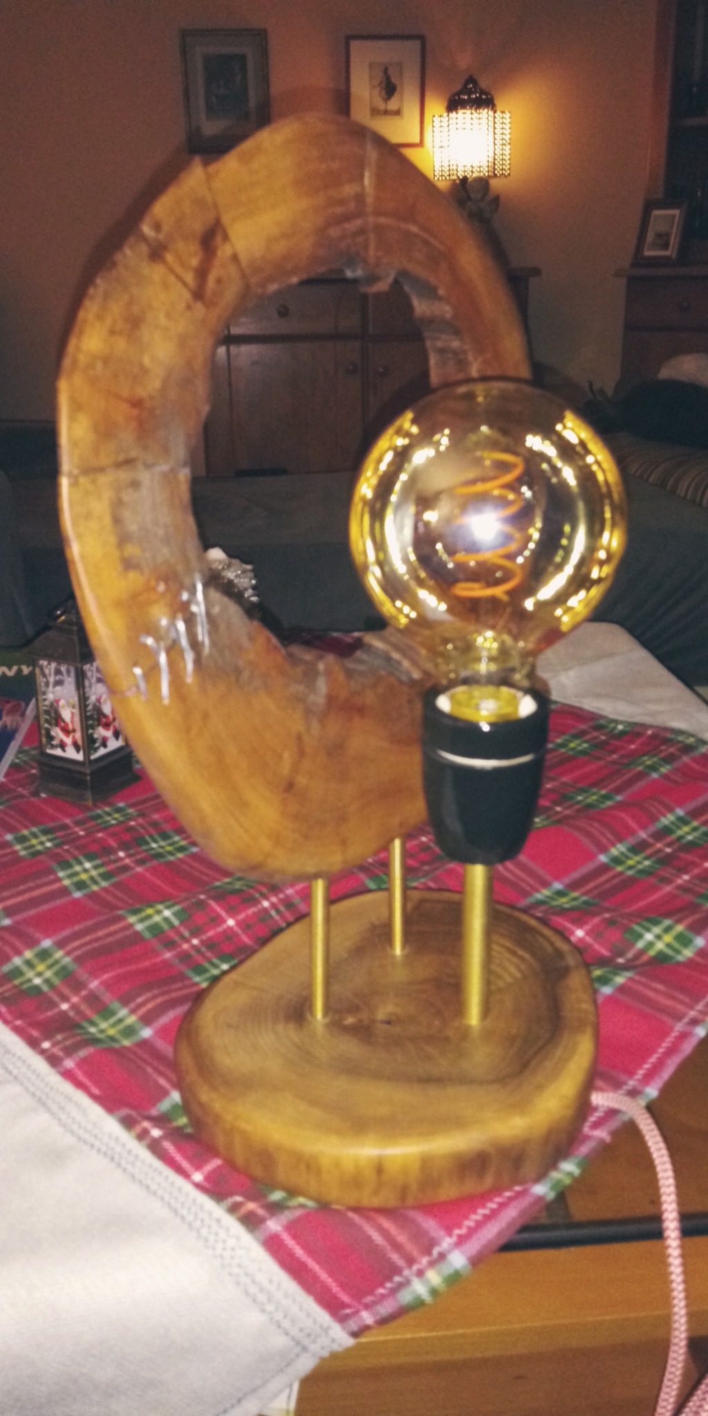 Lampa stołowa DIY z drewnianą podstawą, złotymi prętami i żarówką w stylu retro na stole przykrytym czerwoną kratą.