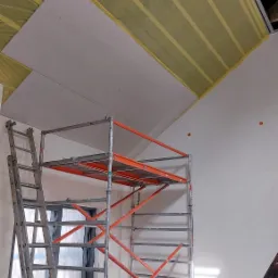 Montaż płyty karton gips na poddaszu w Słońsku, widoczne rusztowanie, drabina i folia zabezpieczająca.