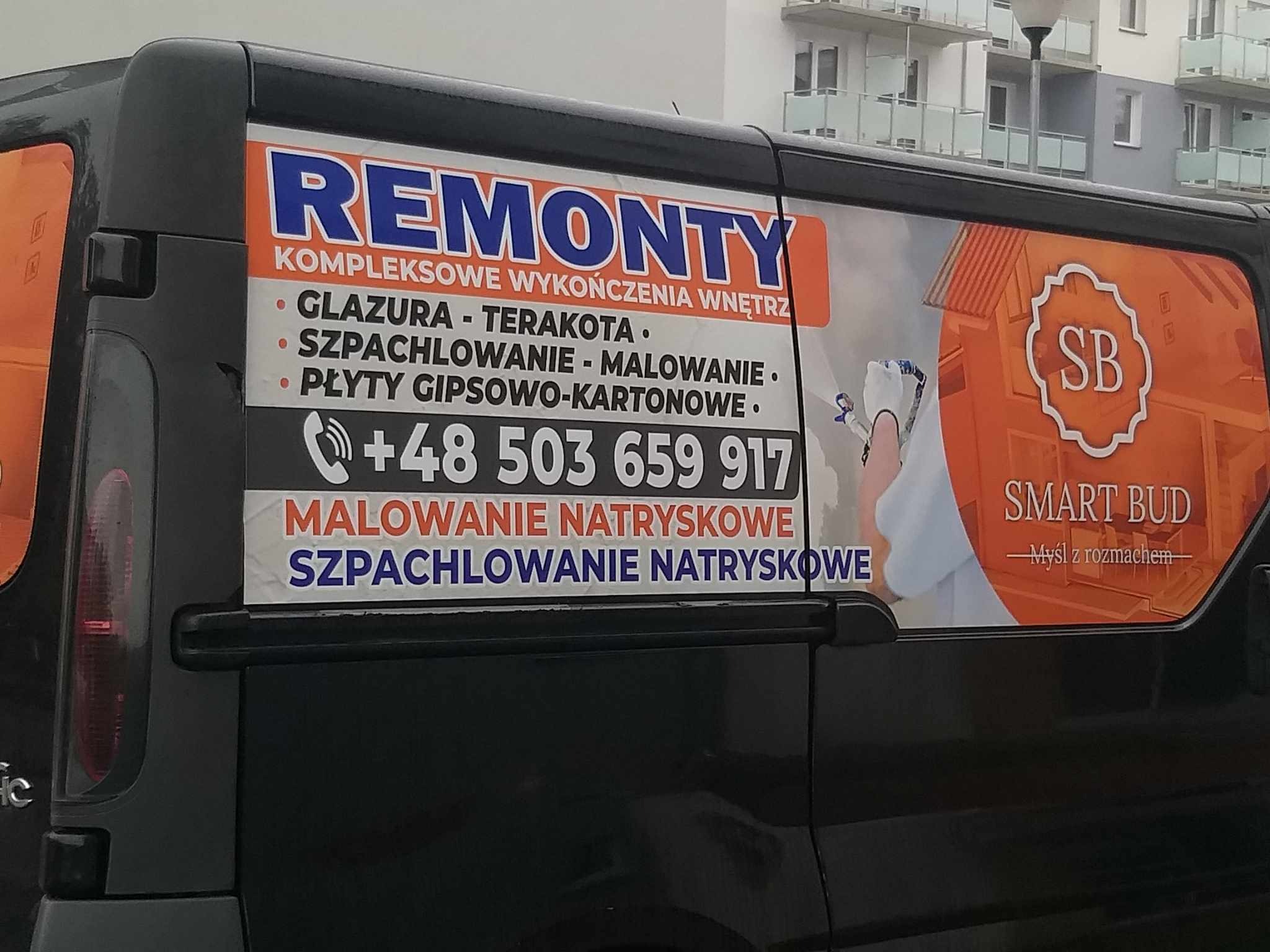 Reklama firmy remontowej na boku czarnego samochodu dostawczego, oferującej kompleksowe wykończenia wnętrz, glazurę, terakotę, szpachlowanie, malowanie, płyty gipsowo-kartonowe, malowanie...