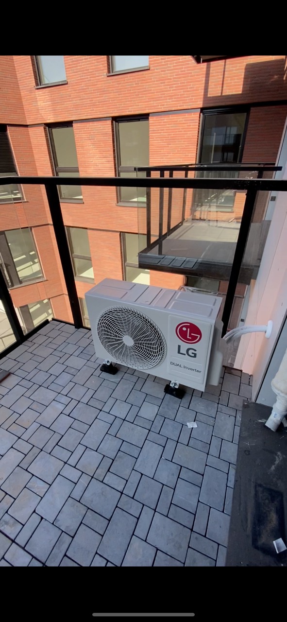 Zewnętrzna jednostka klimatyzacji LG Dual Inverter zamontowana na balkonie nowoczesnego budynku z cegły