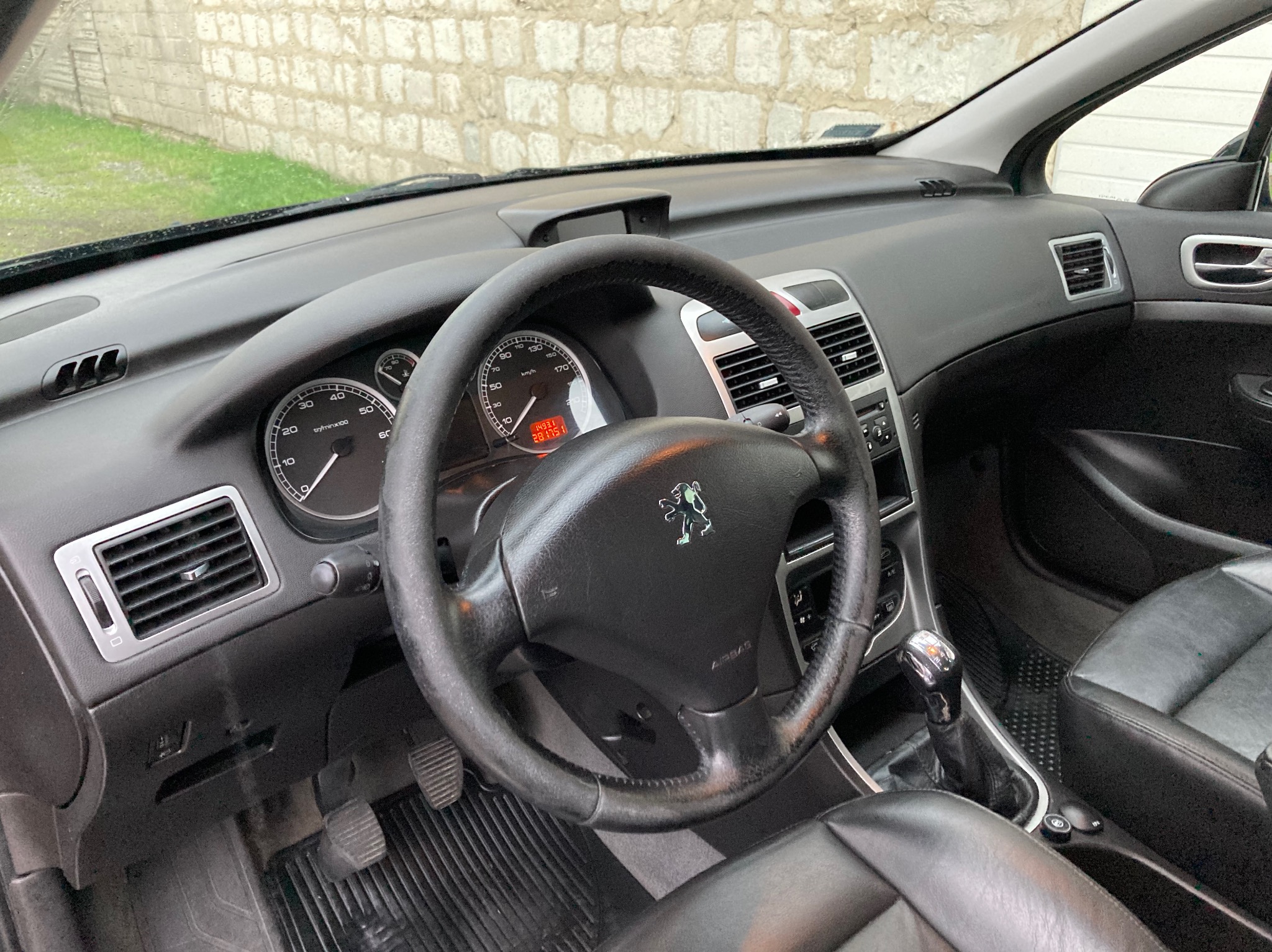 Wnętrze samochodu marki Peugeot 307: deska rozdzielcza, kierownica z logo, skórzane fotele oraz dźwignia zmiany biegów.