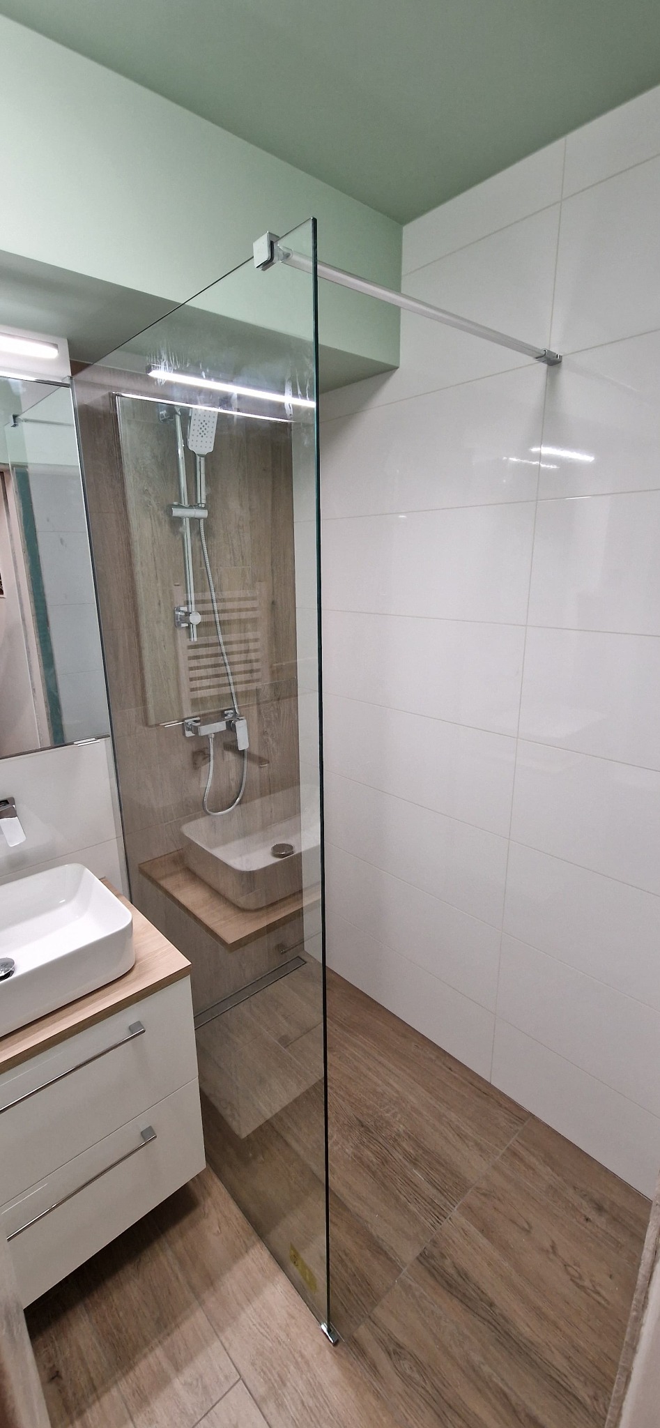 Nowoczesna łazienka z kabiną prysznicową typu walk-in, umywalką nablatową i drewnopodobnymi płytkami na podłodze oraz ścianie w strefie prysznica.