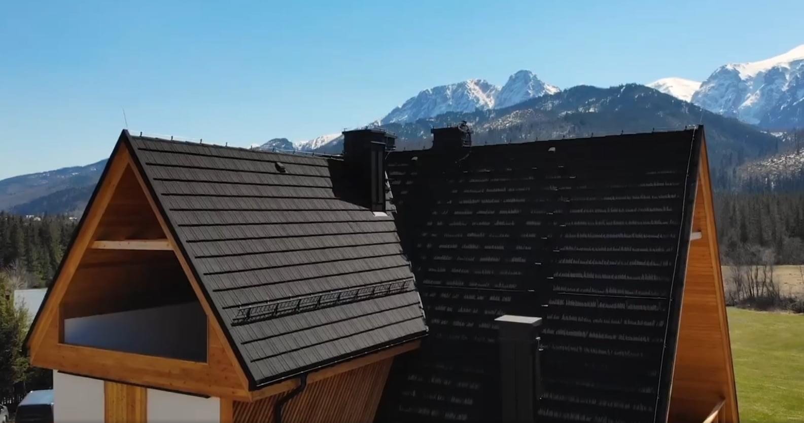 Czarny dach z elementami drewnianymi na tle gór, widok z lotu ptaka.