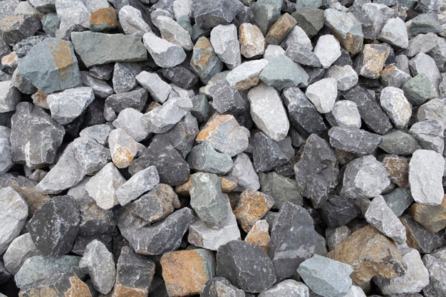 Kupa różnokolorowych kamieni o nieregularnych kształtach, głównie szarych, białych i brązowych, z pojedynczymi elementami o zielonkawym odcieniu.