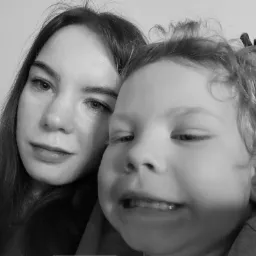 Czarno-białe zbliżenie kobiety i dziecka z kręconymi włosami, uśmiechające się do kamery, z widocznymi detalami twarzy i włosów.
