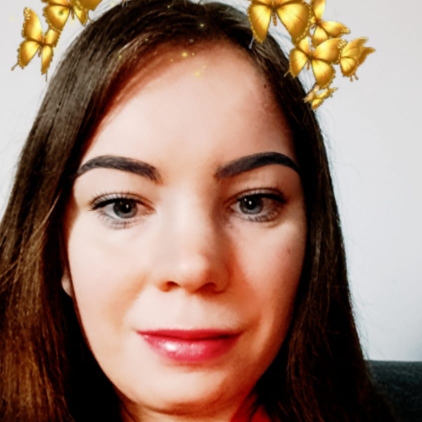 Portret młodej kobiety z brązowymi włosami i cyfrowym filtrem złotych motyli nad głową.