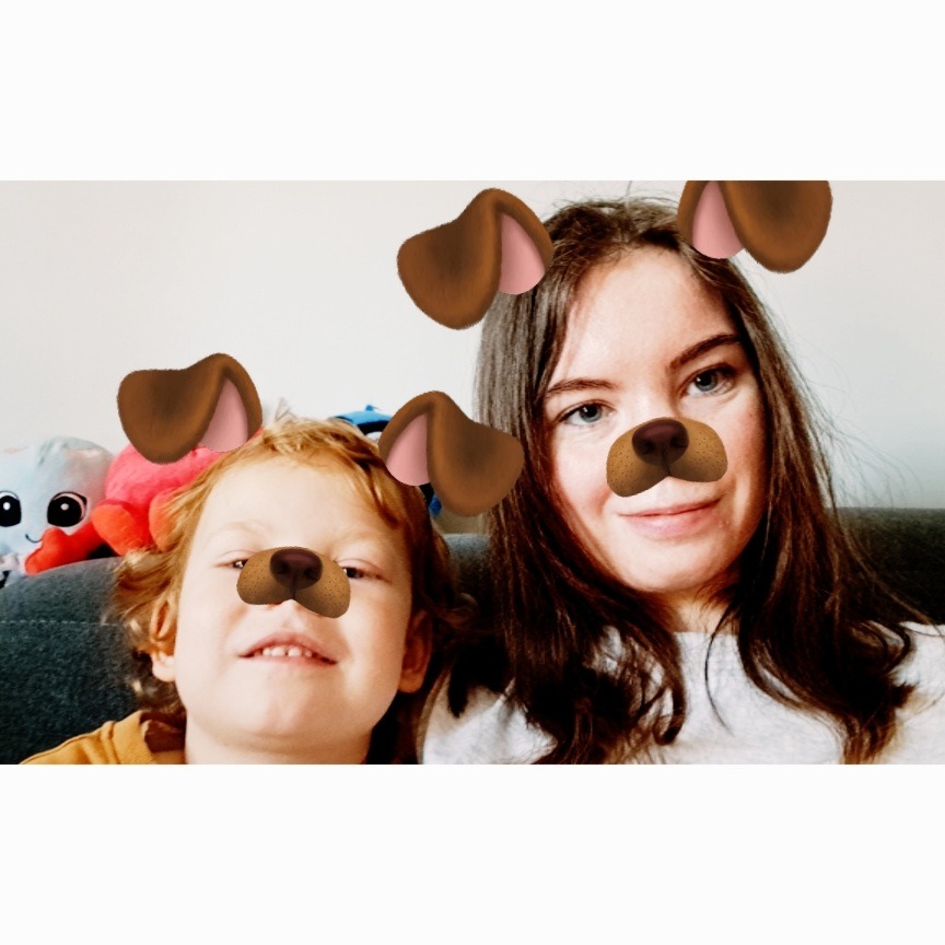 Portret kobiety i dziecka z filtrami psimi, siedzących na kanapie z pluszakami w tle.