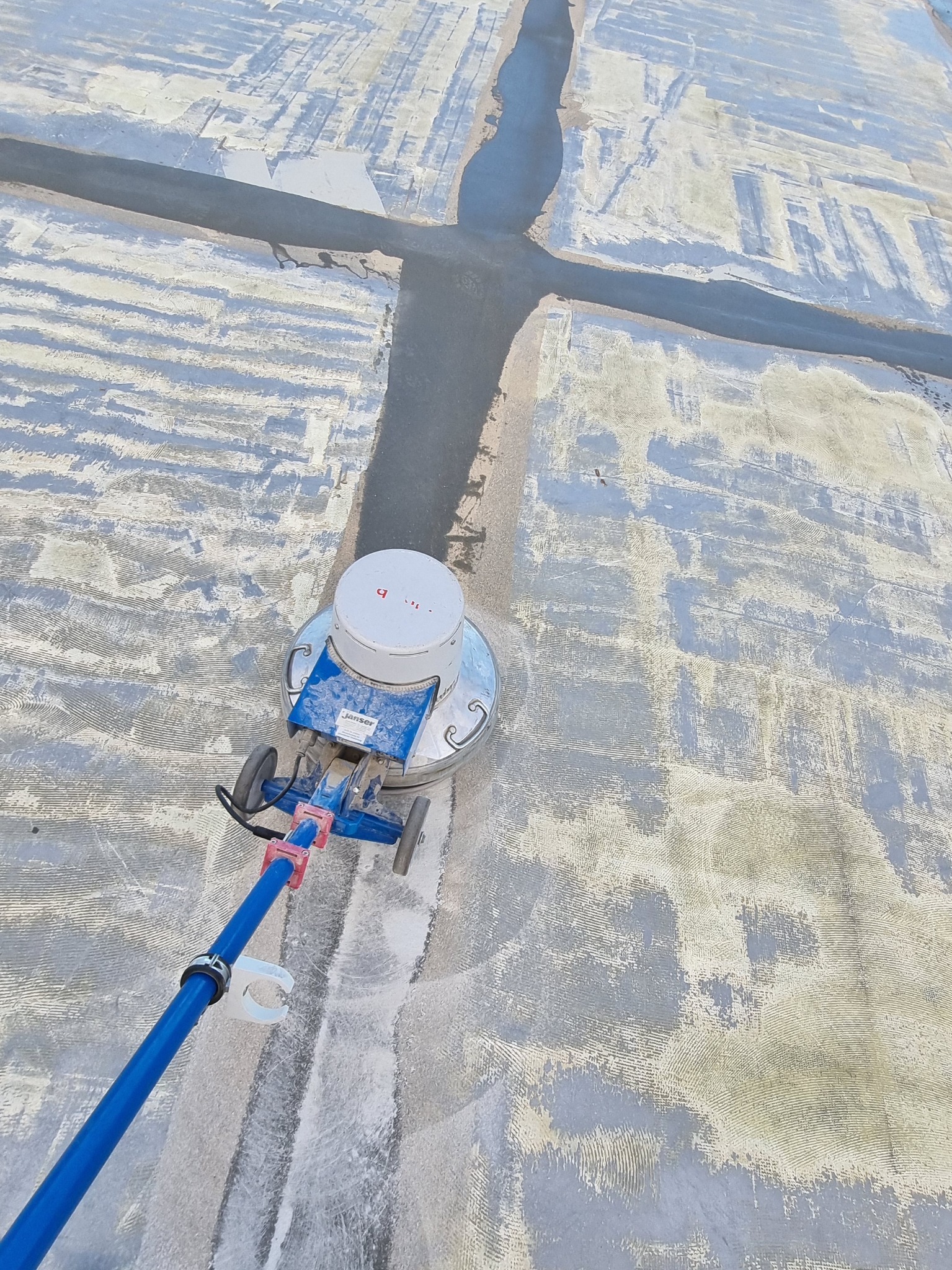 Czyszczenie powierzchni tarasu z kompozytu za pomocą szorowarki z widocznymi śladami po czyszczeniu i wypełnionych szczelinach dylatacyjnych.