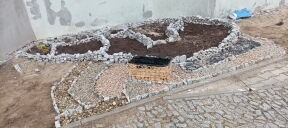 Ogród skalny z różnymi frakcjami kamieni i przygotowanymi rabatami, widok z góry na etapie tworzenia.