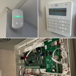 Elementy systemu alarmowego Satel: czujnik ruchu z zieloną diodą, panel sterowania z wyświetlaczem i centrala alarmowa z widoczną elektroniką i okablowaniem.