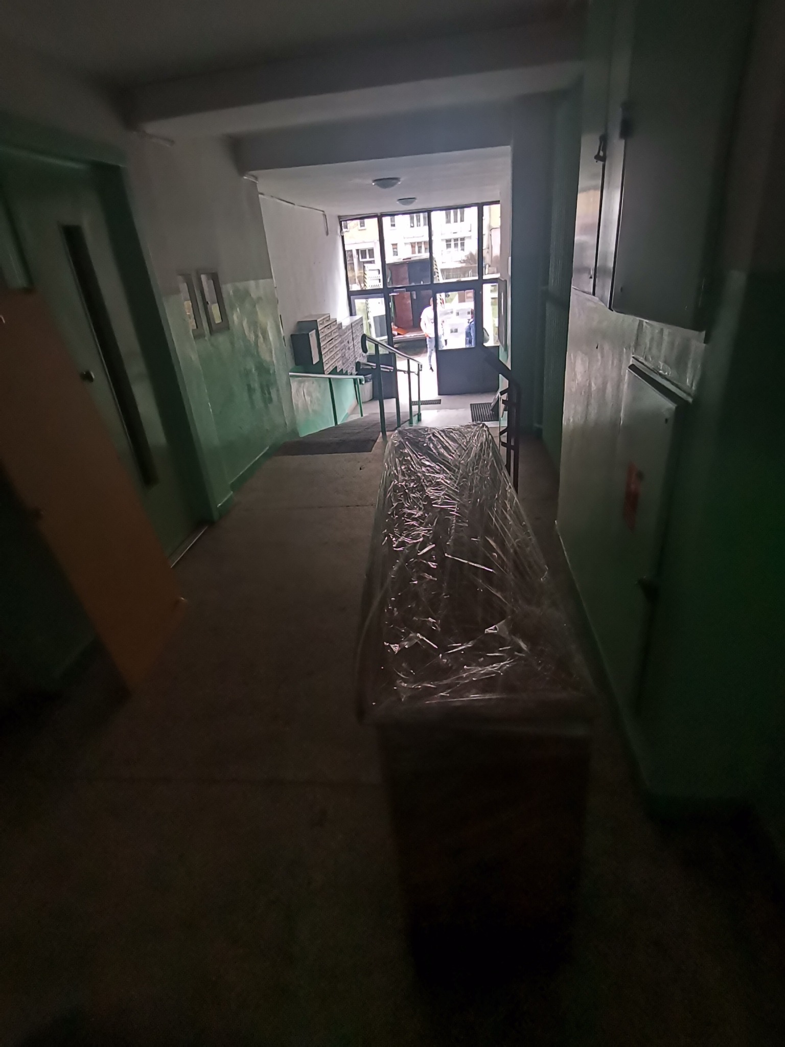 Mebel zabezpieczony folią stretch na korytarzu bloku mieszkalnego, przygotowany do transportu.
