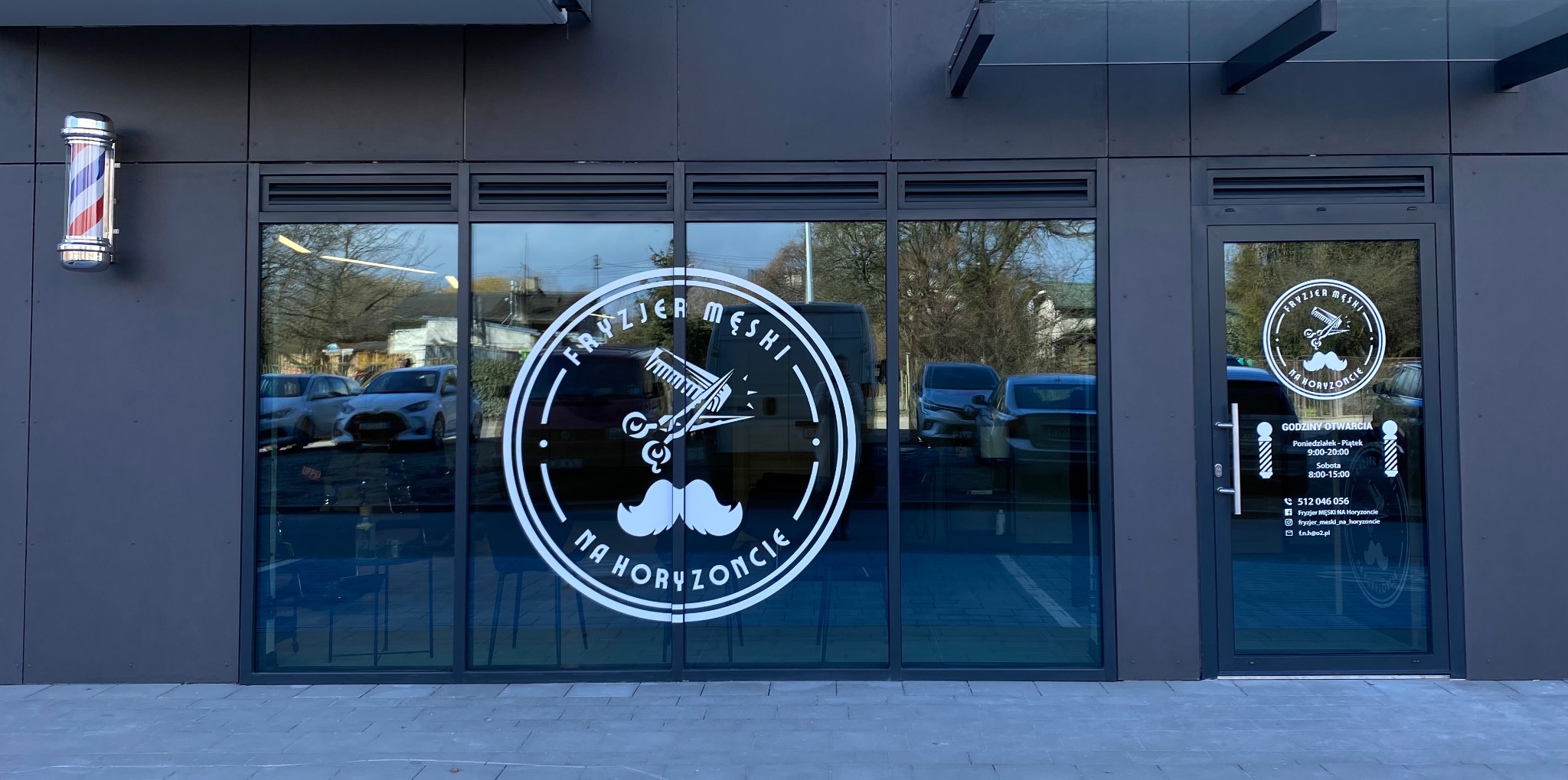 Fasada lokalu z szyldem 'Fryzjer Męski Na Horyzoncie' z barber pole i godzinami otwarcia na drzwiach wejściowych.
