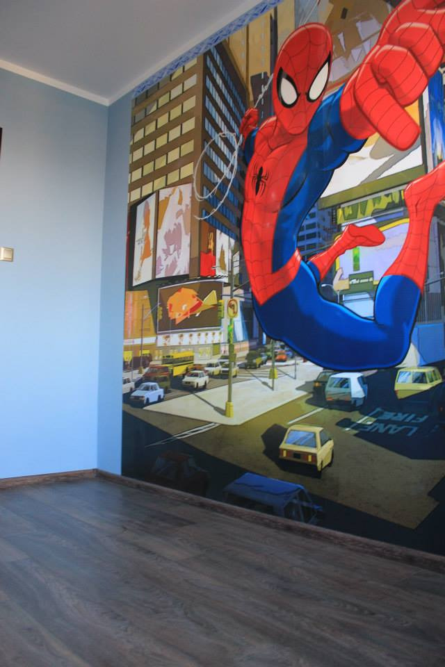 Pokój dziecięcy z fototapetą przedstawiającą Spidermana na tle panoramy miasta, widok na ciemne panele podłogowe.