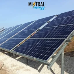 Rząd paneli słonecznych zamontowanych na metalowej konstrukcji, widoczna marka Mistral Energy w g&oacute;rnym rogu, tło to błękitne niebo i odległy krajobraz.