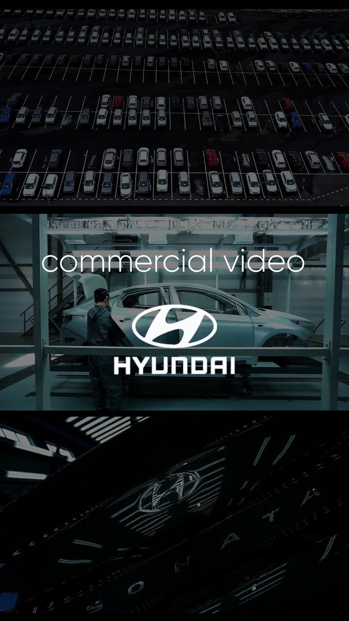 Ujęcie z planu filmowego reklamy samochodowej marki Hyundai, z widokiem na parking pełen aut w tle, pracownika w kombinezonie przy samochodzie oraz zbliżenie na logo i napis Hyundai.