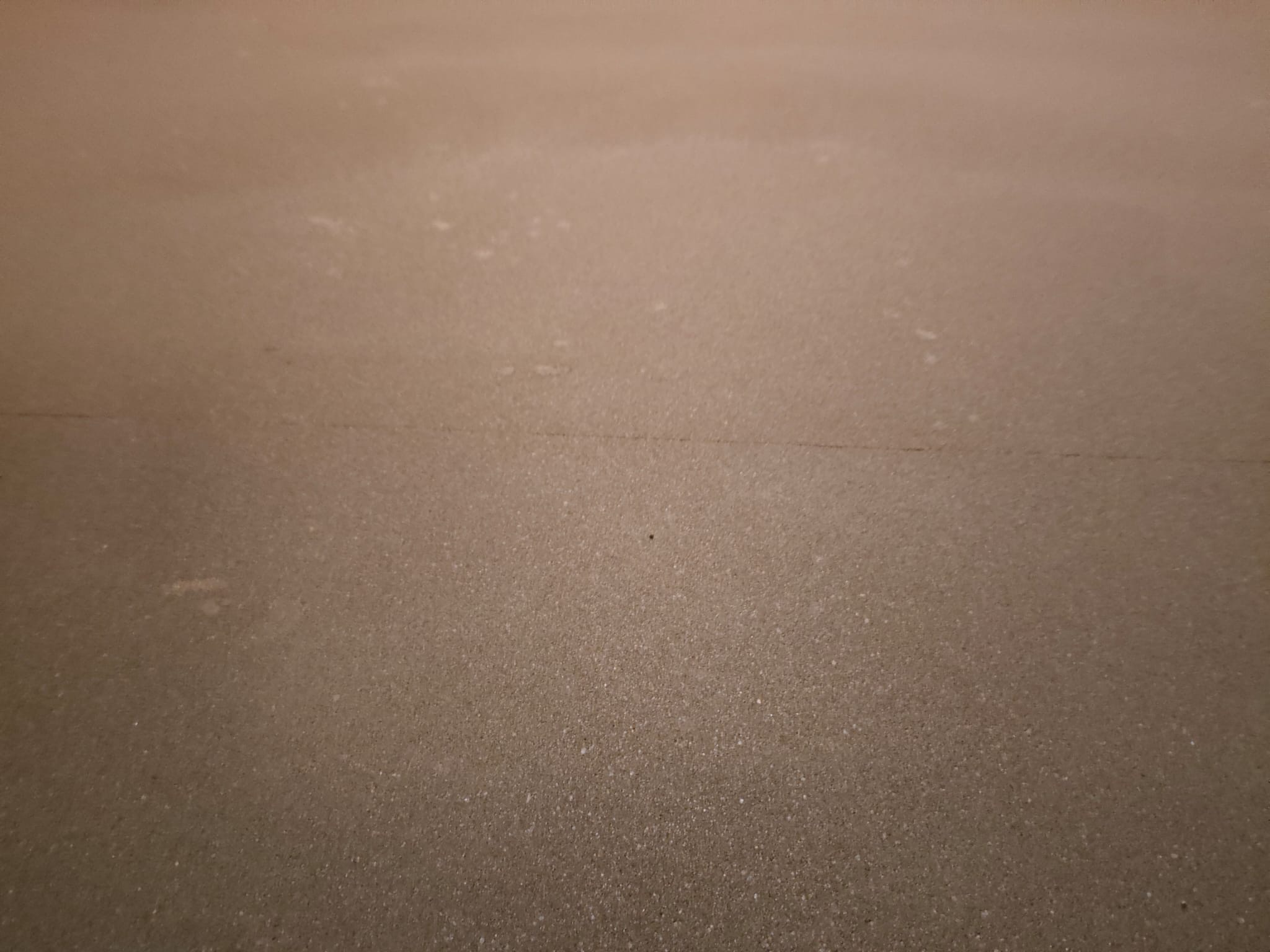 Świeżo wylana, gładka, beżowa posadzka jastrychowa, widoczne delikatne smugi i drobne nierówności na powierzchni.