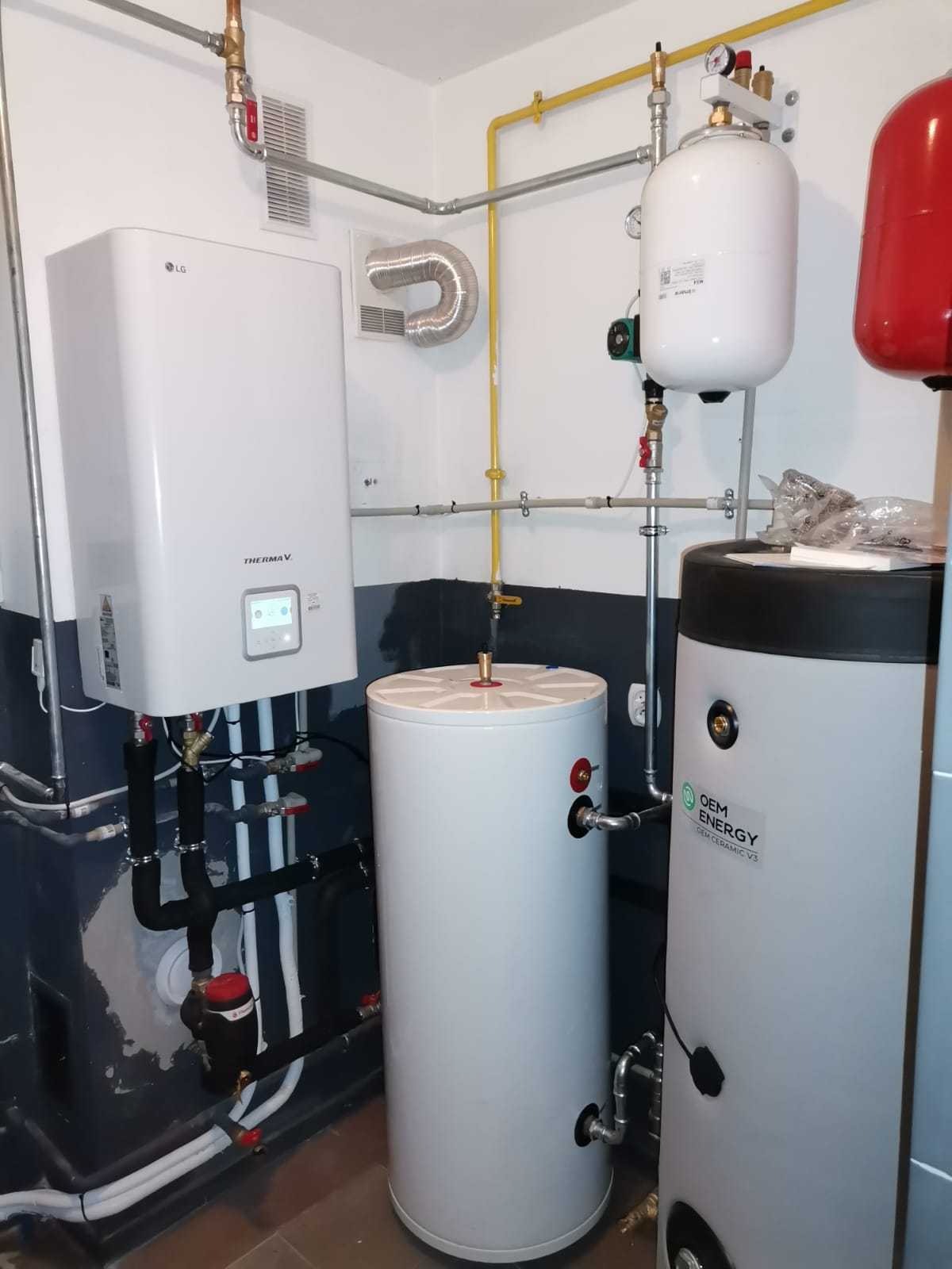 Kotłownia z zamontowaną pompą ciepła LG Therma V, zbiornikami buforowymi i instalacją hydrauliczną w pomieszczeniu z częściowo pomalowanymi ścianami.