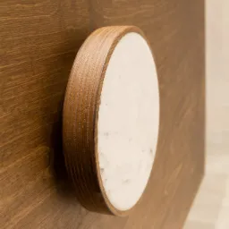 Drewniana szafka z okrągłym uchwytem z marmurowym środkiem, minimalistyczny design.
