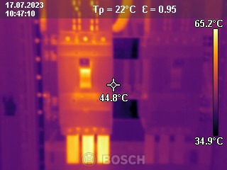 Termowizyjne zdjęcie rozdzielnicy elektrycznej, ukazujące temperaturę różnych elementów. Widoczne wartości temperatur: 44.8°C, 65.2°C, 34.9°C. Na dole logo Bosch.
