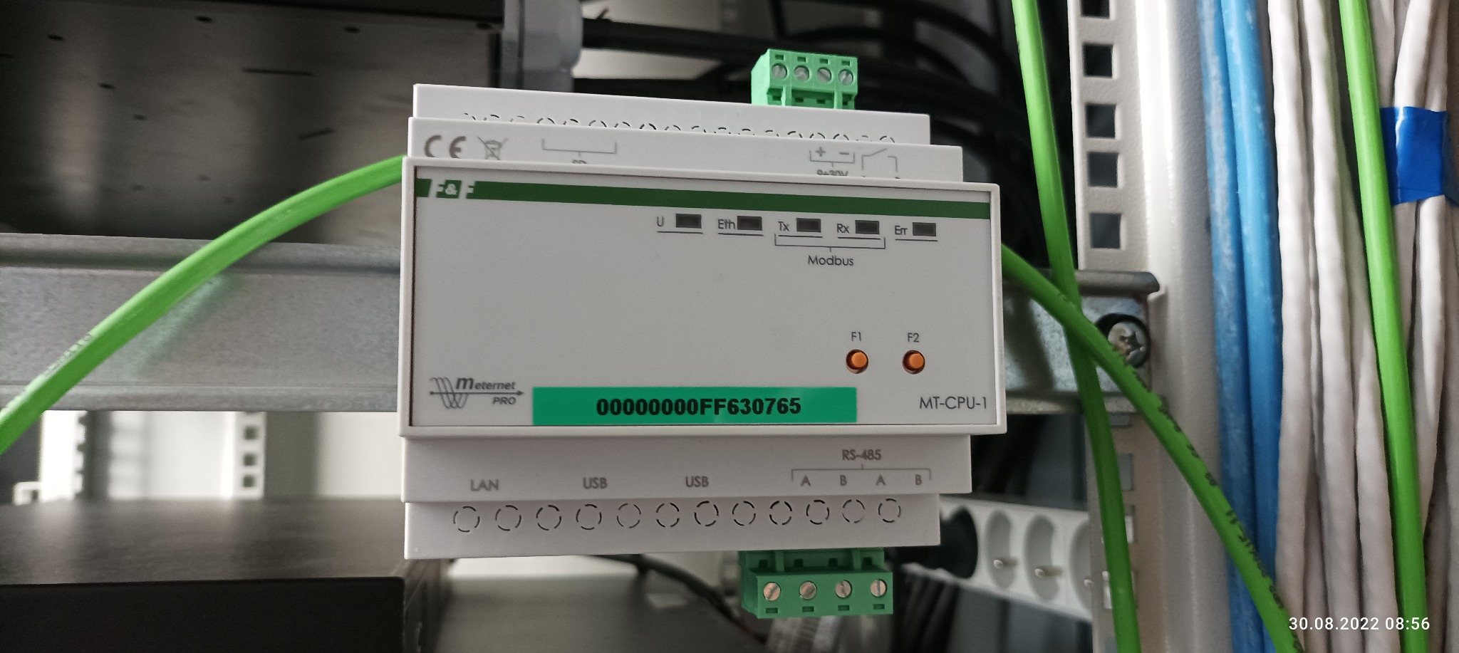 Centrala sterująca MT-CPU-1 marki Meternet Pro z podłączonymi przewodami, widoczne porty LAN, USB i RS-485, diody sygnalizacyjne F1 i F2 świecące na pomarańczowo.