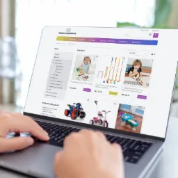 Osoba przegląda na laptopie sklep internetowy z zabawkami, widoczne kategorie zabawek i produkty w ofercie.