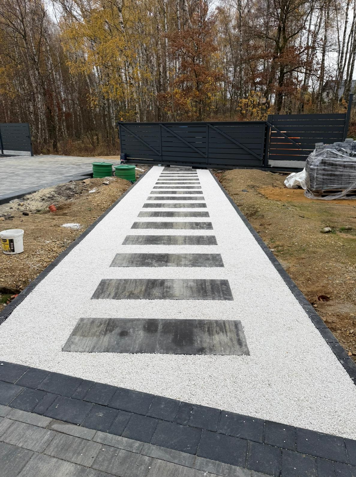 Ścieżka z płyt i białego grysu prowadząca do bramy w Żorach. Estetyczne wykończenie ogrodu z elementami dekoracyjnymi i funkcjonalnymi.