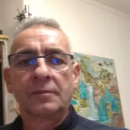 Portret mężczyzny w okularach na tle ściany z obrazem i lampą