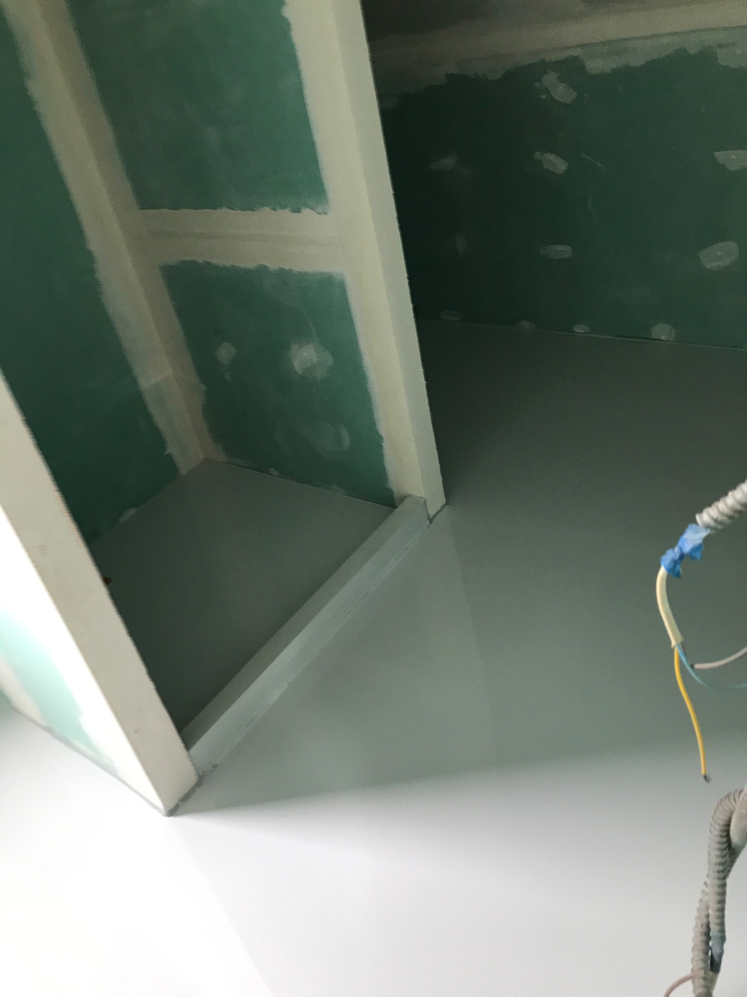 Sufit z zielonymi płytami gipsowo-kartonowymi, łączenia szpachlowane, widoczne przewody elektryczne w peszlu.