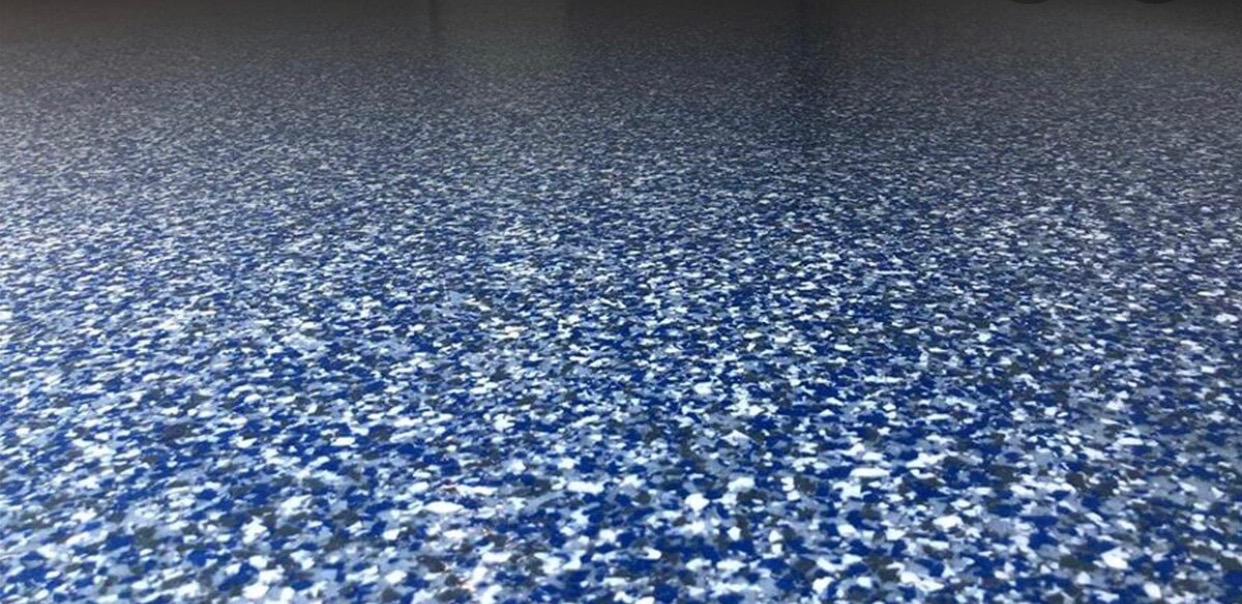 Błyszcząca, niebiesko-szara posadzka żywiczna z efektem lastryko, rozciągająca się w perspektywie do ciemnego tła.