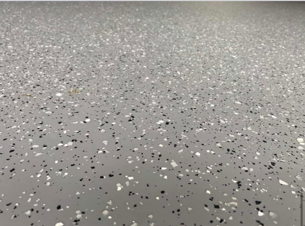 Szara posadzka żywiczna z czarnymi i białymi płatkami, widok z perspektywy podłogi.