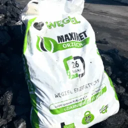 Worek ekogroszku 'Maxiret Orzech' 25 kg, leżący na pryzmie węgla, z widocznym logo i informacjami o wartości energetycznej oraz zawartości siarki.