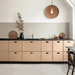 Minimalistyczna kuchnia w stylu skandynawskim z jasnymi drewnianymi szafkami, czarnym blatem i okrągłą dekoracją ścienną z wiszącą żarówką. Na blacie drewniane deski, miski i czarny wazon z suchymi...