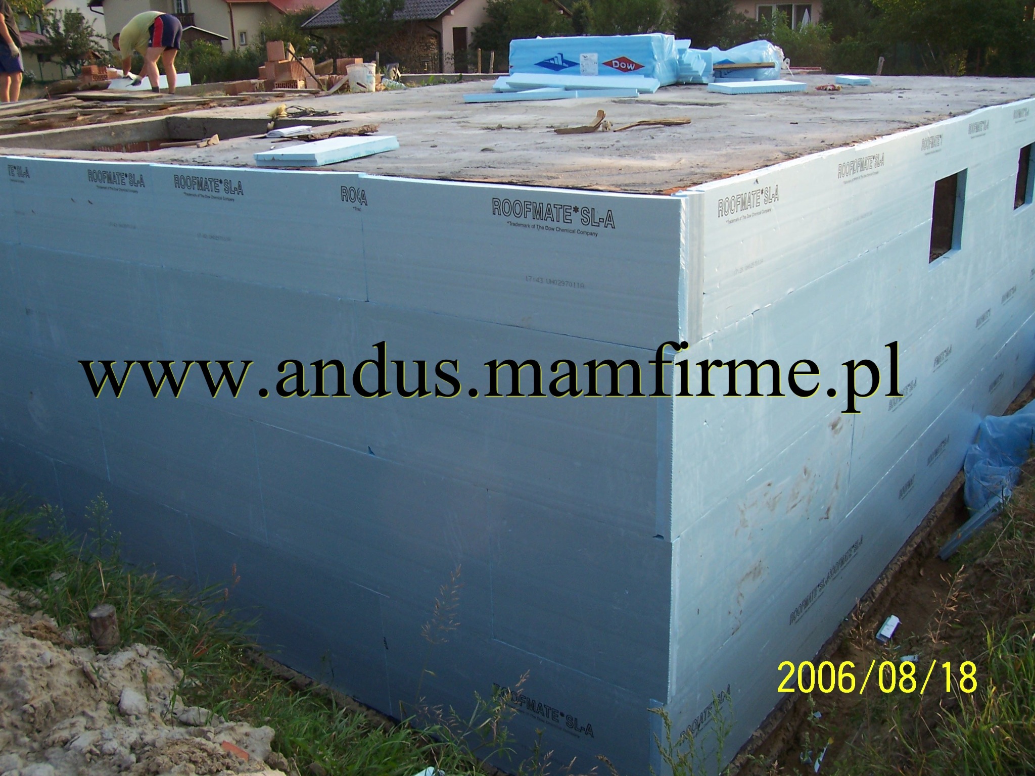 Izolacja fundamentów styropianem ROOFMATE SL-A z widocznymi otworami okiennymi, przygotowana do dalszych prac budowlanych, z datą wykonania zdjęcia 2006/08/18.