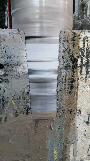 Wiertło koronowe diamentowe w trakcie wiercenia otworu w szarym betonie, widoczne ślady po wierceniu i żółte oznaczenia na powierzchni.