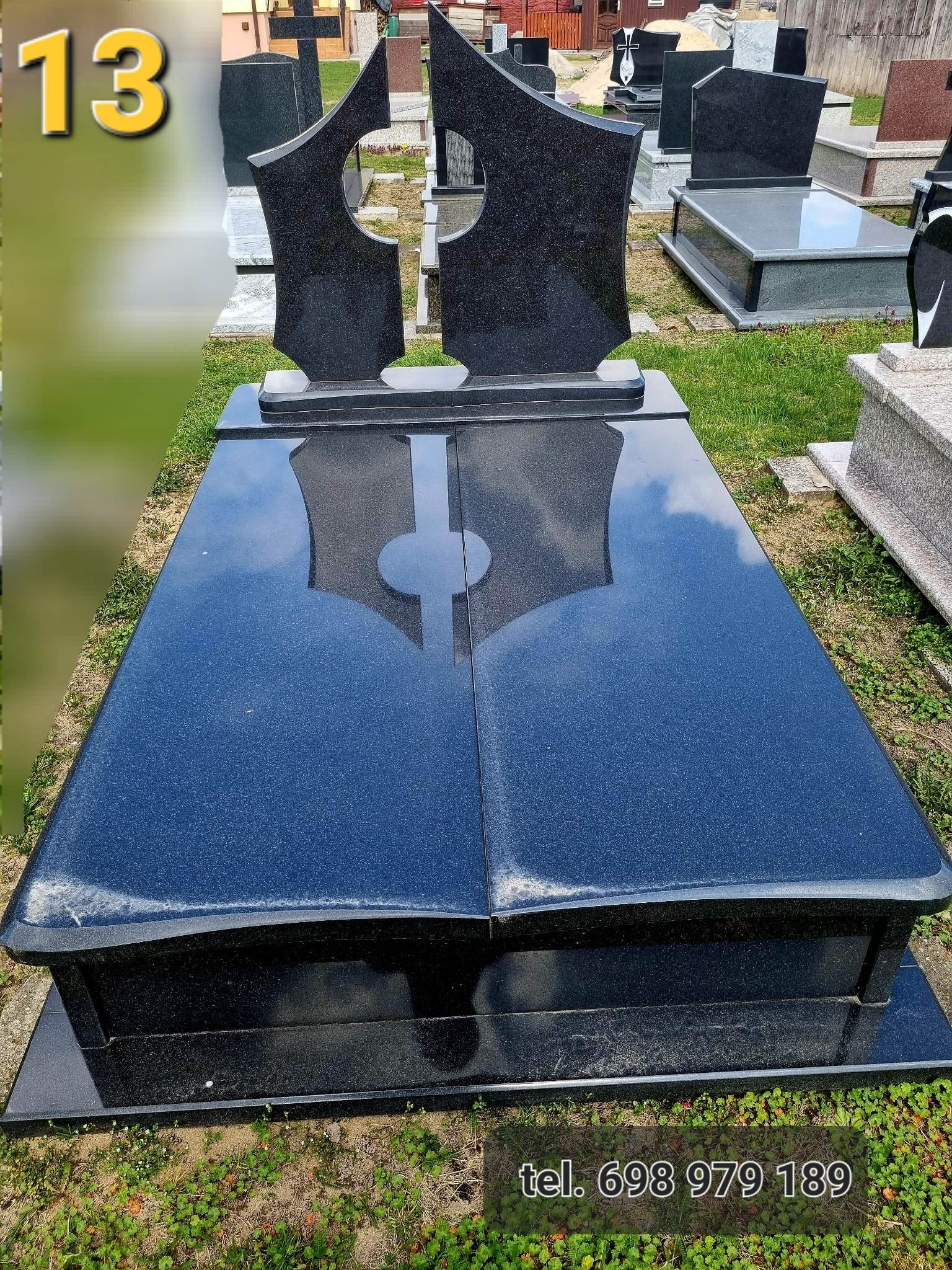 Czarny, podwójny nagrobek z granitu z nowoczesnym, geometrycznym wzorem w kształcie dwóch połączonych elementów z okrągłymi wycięciami, ustawiony na trawniku, z numerem telefonu widocznym na dole...