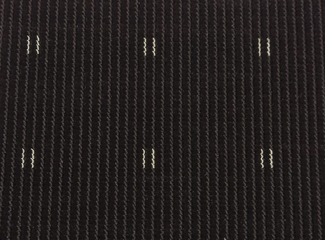 Ciemna wykładzina dywanowa z pionowymi prążkami i drobnymi, nieregularnymi, jasnymi akcentami na całej powierzchni.