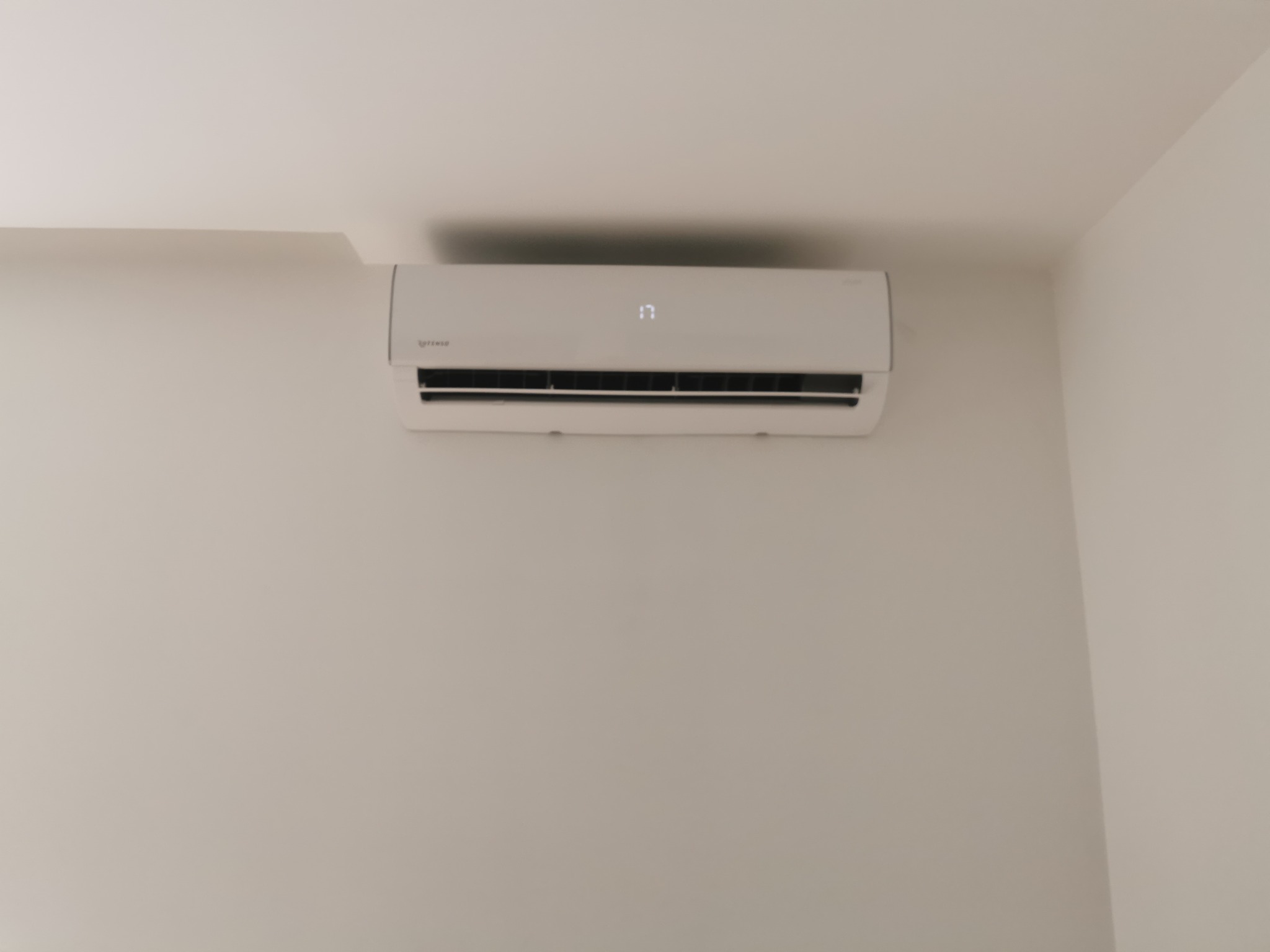 Biały klimatyzator ścienny marki Rotenso, ustawiony na 17 stopni, zamontowany w rogu jasnego pokoju.