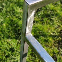 ParvisWelder Michał Gawarkiewicz - Fragment spawanej, metalowej konstrukcji na tle trawy, widoczne ślady szlifowania i spawania, ostre krawędzie.