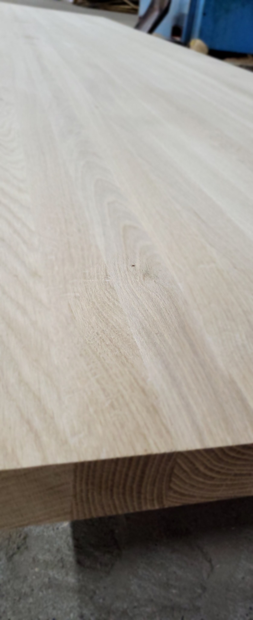 Szlifowana deska z jasnego drewna, widoczne słoje i faktura, ujęcie z bliska, ukazujące gładką powierzchnię.