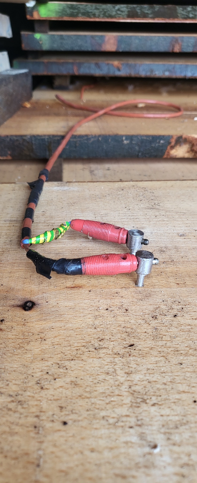 Używane przewody z czerwonymi wtykami i izolacją z taśmy, leżące na drewnianej powierzchni w Bachórz.