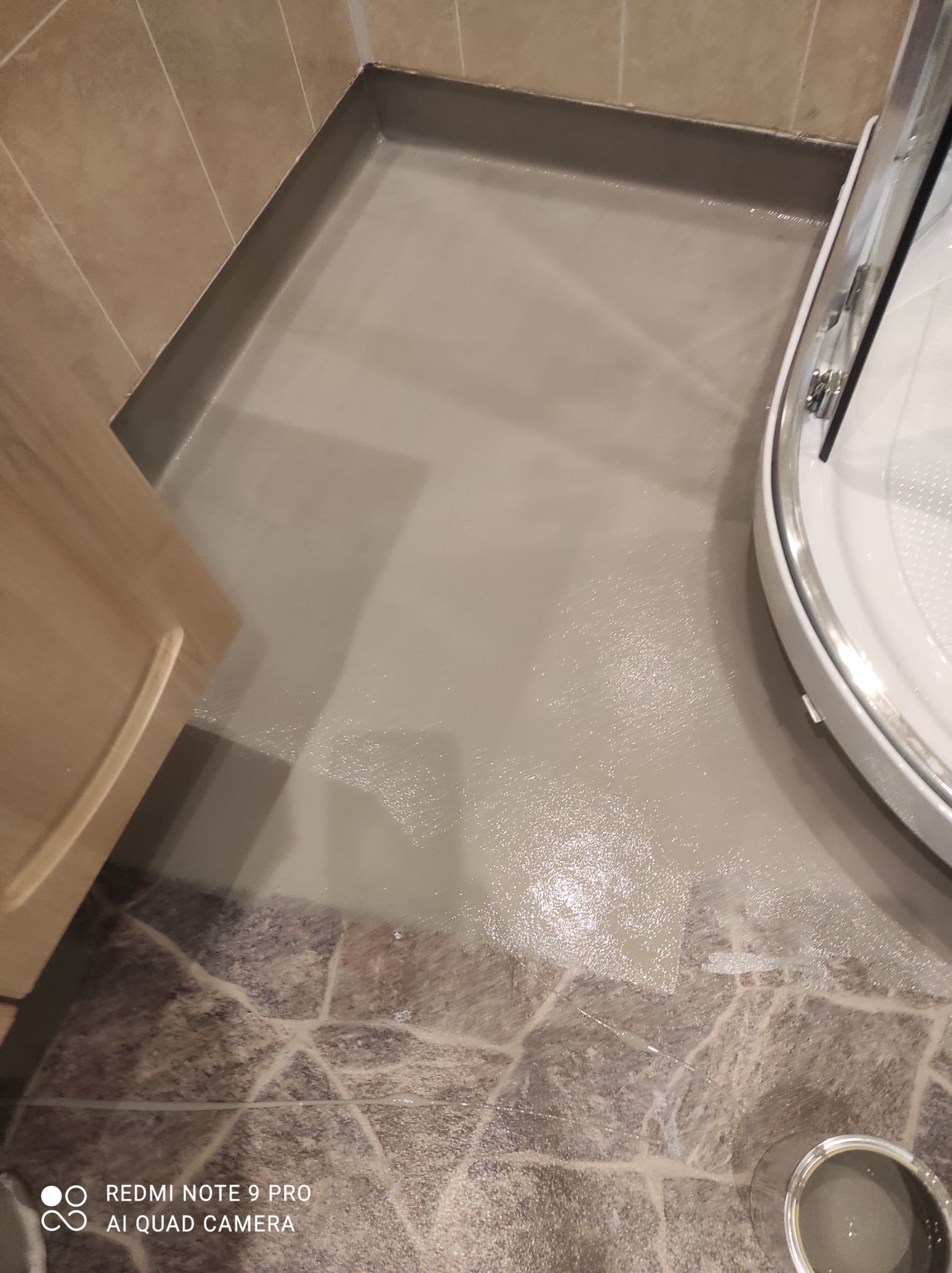 Wylewka samopoziomująca w kabinie prysznicowej, widoczna granica z płytkami na podłodze, krawędzie przy ścianach i brodziku zabezpieczone.