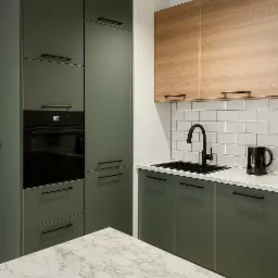 Nowoczesna kuchnia: zielone szafki z czarnymi uchwytami, drewniane szafki wiszące, marmurowy blat i czarna armatura. Minimalistyczny design, oświetlenie punktowe.