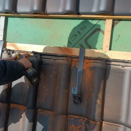 Pikot - Dekarz szlifuje dachówkę szlifierką kątową podczas montażu łat i kontrłat na zielonej membranie dachowej.