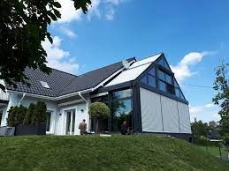 Zadaszony taras w Wien z nowoczesną konstrukcją i roletami przeciwsłonecznymi, widok z zewnątrz na tle zieleni i błękitnego nieba.