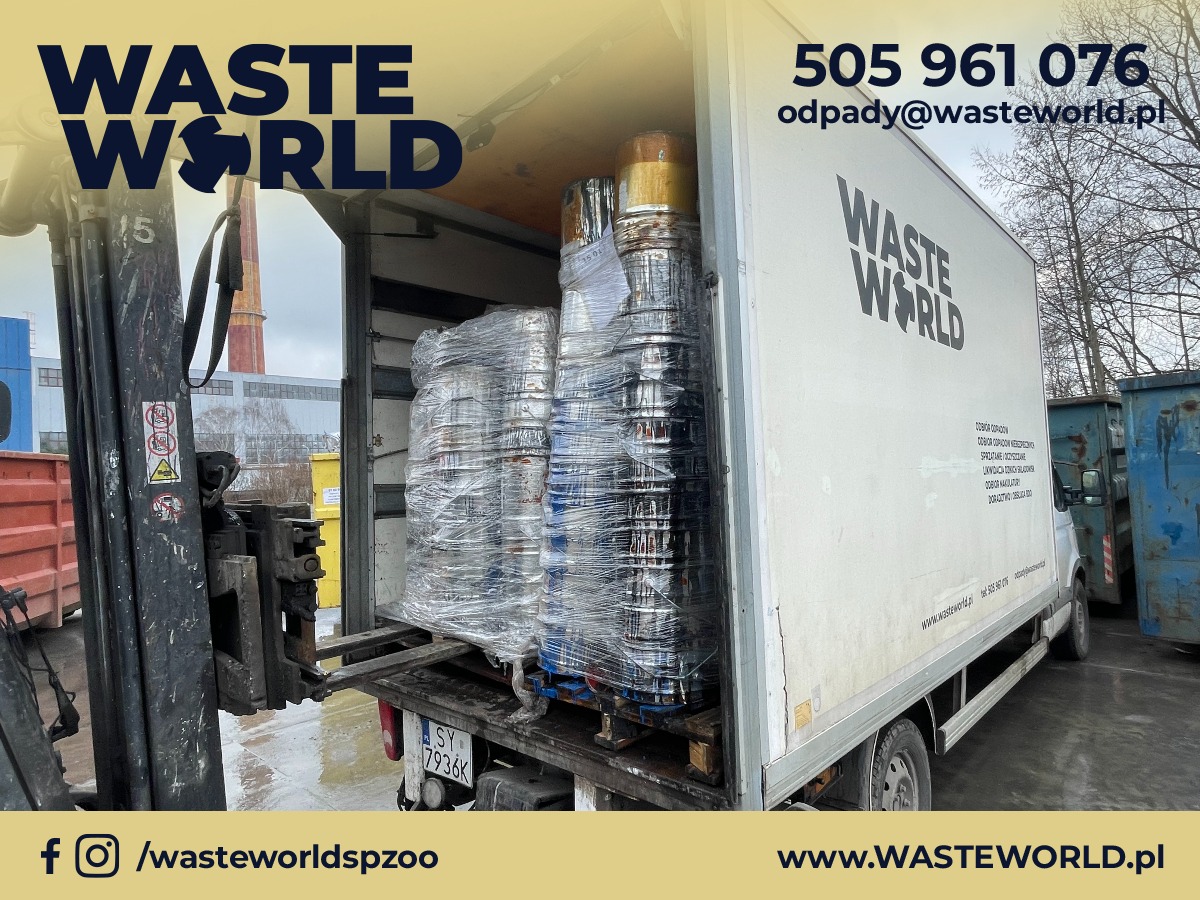 Załadunek palety z metalowymi beczkami na platformie widłowej wózka widłowego do wnętrza samochodu dostawczego Waste World. W tle widoczny komin przemysłowy i inne pojemniki na odpady.