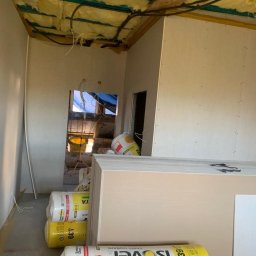 Teradom Grzegorz Osyp - Wnętrze w trakcie wykańczania: izolacja stropu wełną mineralną, ściany obłożone płytami kartonowo-gipsowymi, materiały budowlane Isover na podłodze.