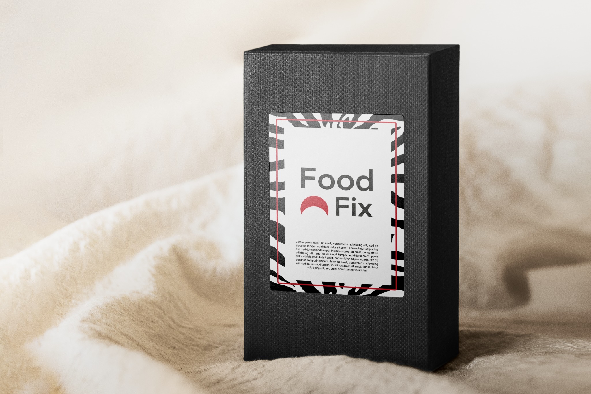 Czarny, teksturowany kartonik z naklejoną etykietą 'Food Fix' w ramce z motywem zebry, umieszczony na kremowym, pogniecionym materiale.
