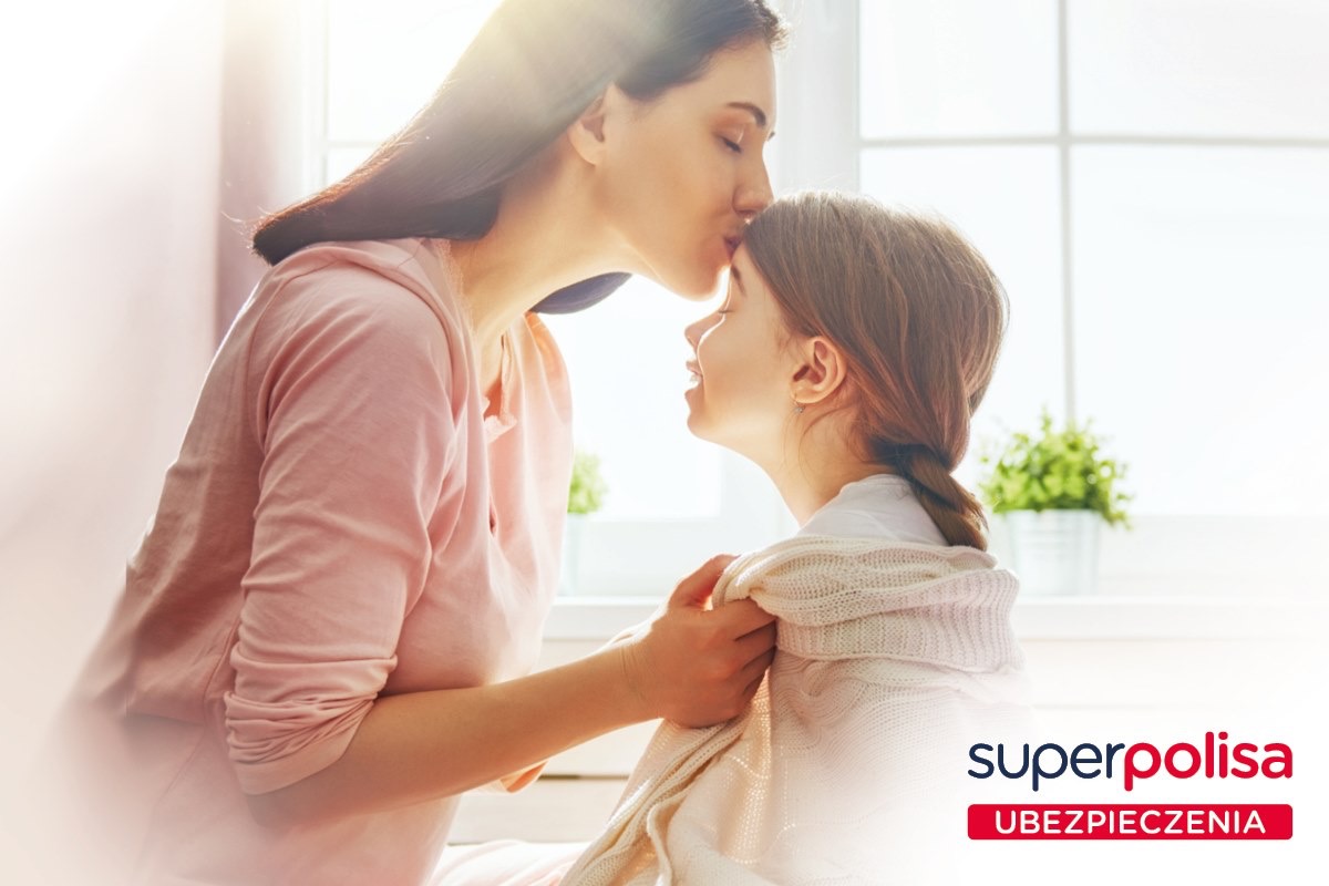Matka całuje córkę w czoło w jasnym wnętrzu, w tle roślina doniczkowa i logo firmy ubezpieczeniowej Superpolisa.