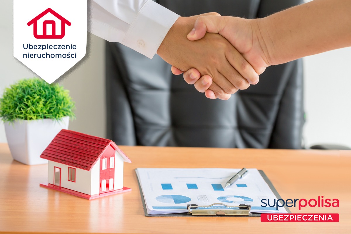 Uścisk dłoni nad stołem z modelem domu, dokumentami z wykresami i logiem firmy ubezpieczeniowej.